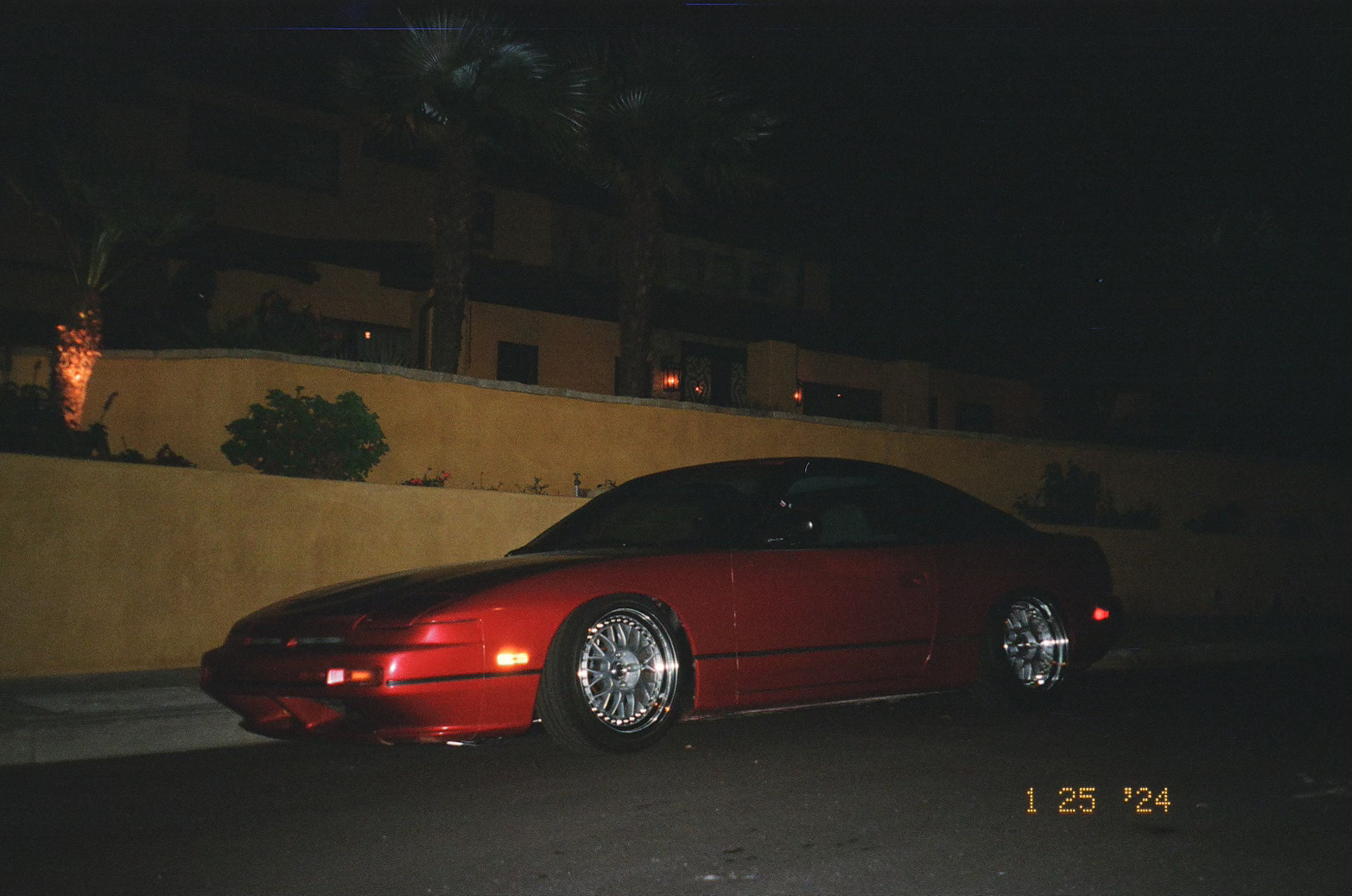 Flash photography of a red Nissan 240SX parked in a neighborhood.